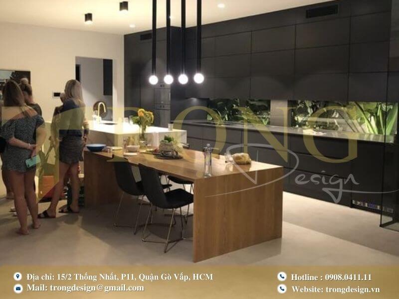 Bếp sang trọng với đảo bếp lớn, bàn ăn dài và hệ thống đèn thả trần ấn tượng.