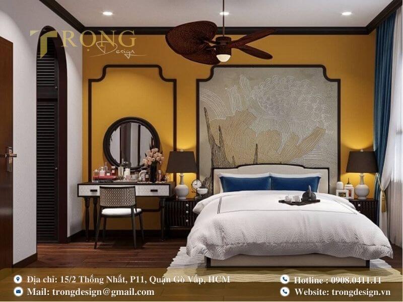 Phòng ngủ Indochine ấm cúng với tường vàng mustard và họa tiết hoa sen tinh xảo.
